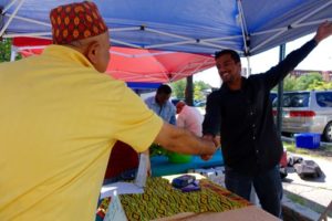 a farmer shaking hands with a customer at a farmers market