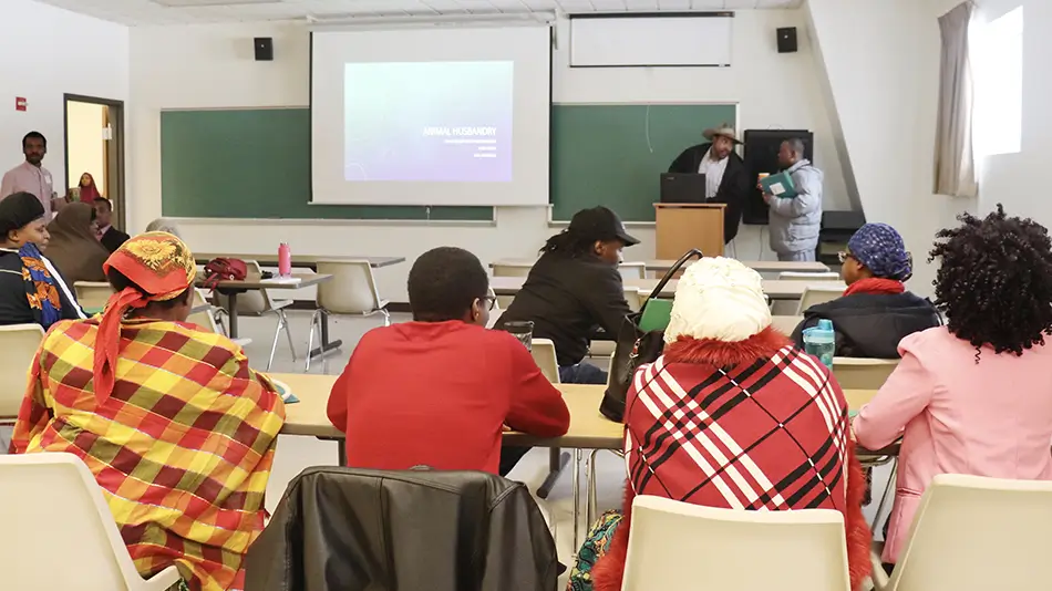 farmer training refugees at tables with a presentation going on