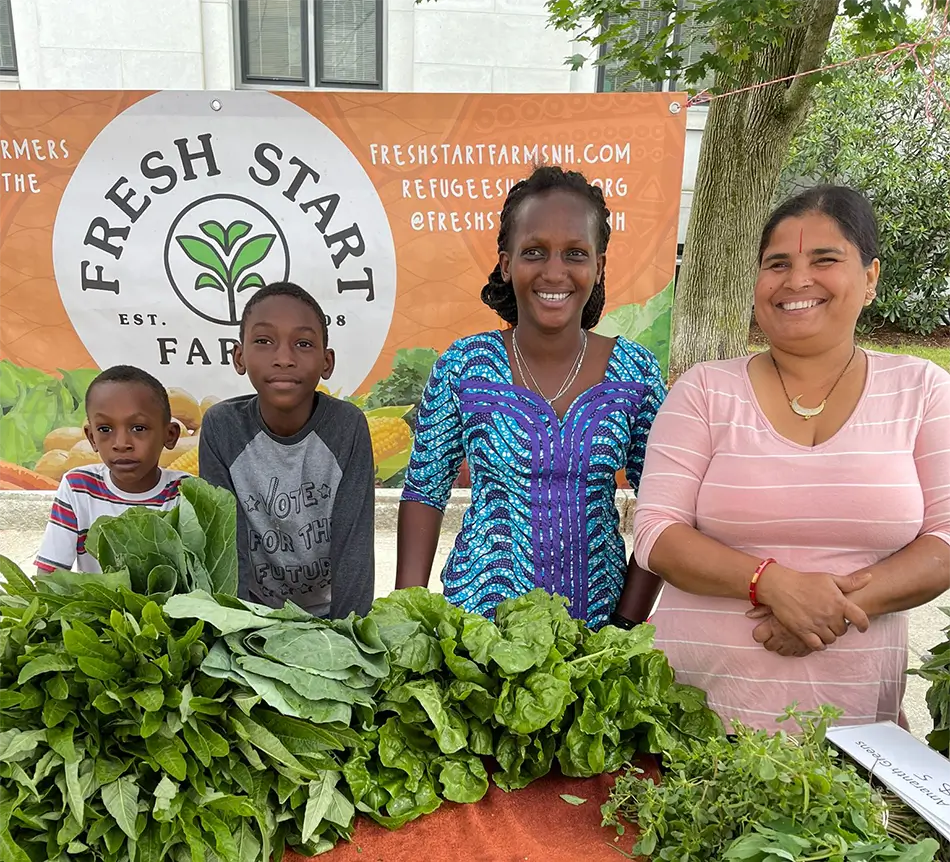 two mixed culture women smiling at a farmers market with two young boys