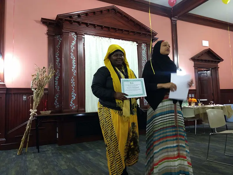 two mixed culture women holding certificates at a ceremony